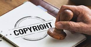 A close-up of a person's hand pressing an official legal stamp onto a book cover displaying the word copyright.